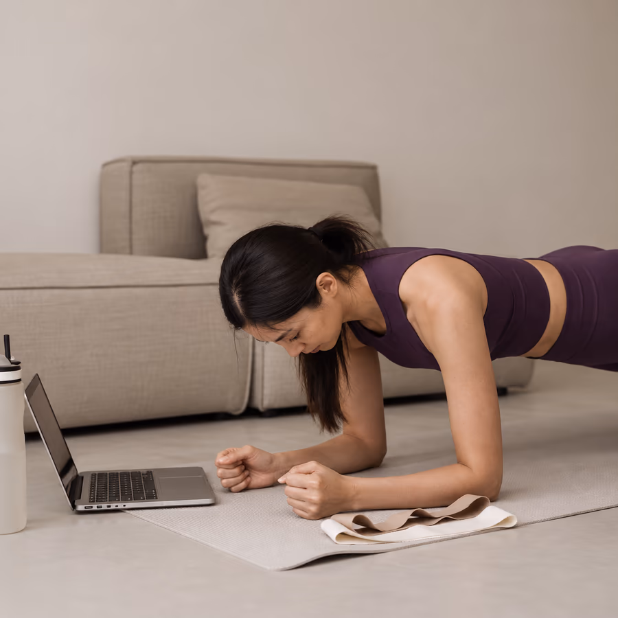 A woman holding a plank in front of her laptop